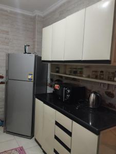 a kitchen with white cabinets and a refrigerator at Luxury Apartment In Sheikh Zayed - Jannah 2 Compound in Sheikh Zayed