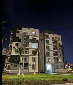 a tall building with two palm trees in front of it at Luxury Apartment In Sheikh Zayed - Jannah 2 Compound in Sheikh Zayed