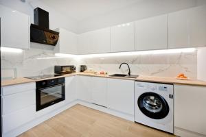 eine Küche mit weißen Schränken und einer Waschmaschine und einem Trockner in der Unterkunft Apartamenty IN Leśna in Hel