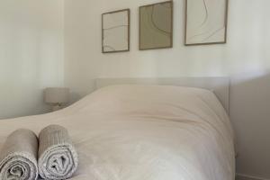 Un dormitorio con una cama blanca con toallas. en L'Appart 32 - Appartement confortable et au calme, en Annecy