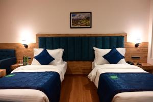 ein Hotelzimmer mit zwei Betten und blau-weißen Kissen in der Unterkunft Click collection Gangtok in Gangtok