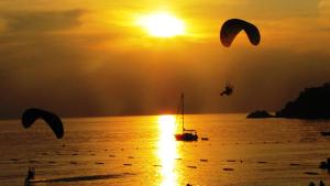 two people flying kites over the ocean at sunset at Sundia By Liberty Oludeniz in Oludeniz