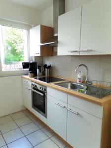 a kitchen with white cabinets and a sink at Köster Apartment in Olpe