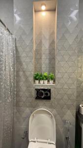 a bathroom with a toilet and two plants on a wall at NIVAASe STAYS in New Delhi +45 photos