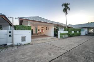 ein Haus mit einer Einfahrt und einer Palme in der Unterkunft Sorrento Pool Villa Bang Lamung Pattaya in Ban Rong Po