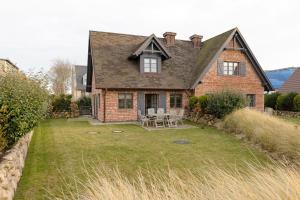 een groot bakstenen huis met een tuin met stoelen bij Dünenhafer in List