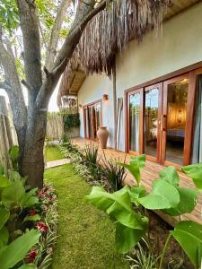 ein Haus mit einem Baum und einer Holzterrasse in der Unterkunft Casa Preguiça Corumbau in Corumbau
