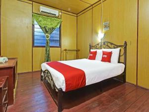 Un dormitorio con una cama con almohadas rojas y una ventana. en OYO 90620 Mahseer Chalet, en Kuala Tahan