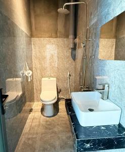 um banheiro com um vaso sanitário branco e uma pia em T-Homestay Bình minh xanh 