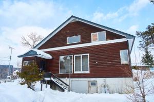 a brown house with a garage in the snow at HETA Niseko in Niseko