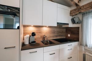 een keuken met witte kasten en een spoelbak bij LAAX Homes Casa Partnun 2-9 in Laax-Murschetg