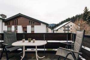een terras met een tafel en stoelen op een balkon bij LAAX Homes Casa Partnun 2-9 in Laax-Murschetg