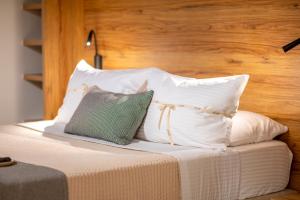 uma cama com almofadas brancas e uma almofada verde em EPTA Houses em Marmari