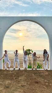 un groupe de femmes debout sous une arche sur la plage dans l'établissement Borrbo Beach Hostel Gokarna, à Gokarna