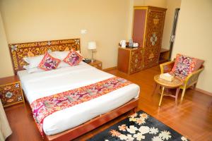 a bedroom with a large bed and a chair at Hotel Harmika - Spiritual retreat with garden & Stupa view in Kathmandu +70 photos