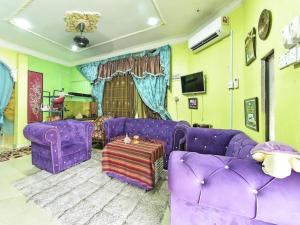 Una sala de estar con muebles morados y un sofá morado. en OYO 90740 Paddington Lodge, en Kubang Kerian