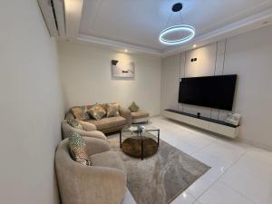 ein Wohnzimmer mit zwei Sofas und einem Flachbildfernseher in der Unterkunft مارينا بلس 2 in Dschidda