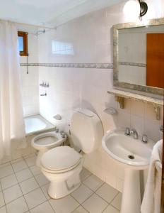 Baño blanco con aseo y lavamanos en Graz Hauser Cabañas en Villa General Belgrano