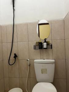 a bathroom with a toilet and a mirror on the wall at Raphi house in Yogyakarta