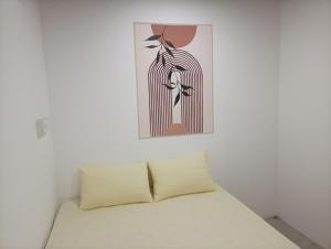 a bed in a white room with a painting on the wall at Airport Transit Motel in Katunayaka