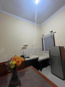 a kitchen with a refrigerator and a vase of flowers on a table at Raphi house in Yogyakarta