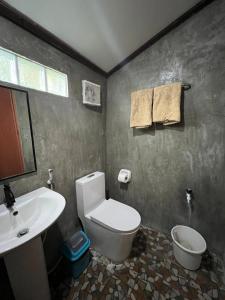 ein Badezimmer mit weißer Toilette und Waschbecken in der Unterkunft Siargao Tropic Hostel in General Luna