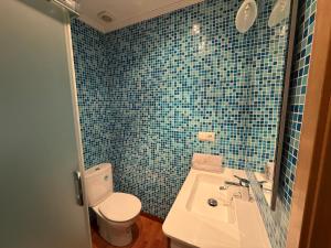 Un baño con azulejos azules, inodoro y lavabo. en La Casucha, en Caboalles de Abajo 16 fotos más