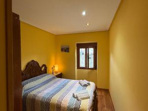 Dormitorio amarillo con cama y ventana en La Casucha, en Caboalles de Abajo