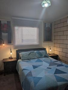 een slaapkamer met een bed, 2 lampen en een raam bij Lighthouse Lodge in Devonport
