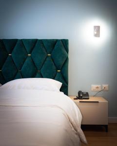 a bedroom with a bed with a green headboard at Leo Hotel in Kukës