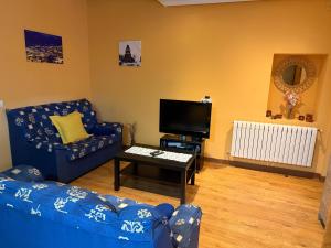 Una sala de estar con un sofá azul y un televisor en La Casucha, en Caboalles de Abajo