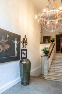 ein Kronleuchter und ein Mülleimer in einem Raum mit Treppe in der Unterkunft La Manufacture Royale 1739 in Montolieu