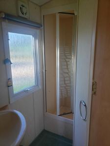 ein Badezimmer mit Dusche und Waschbecken und einem Fenster in der Unterkunft l Aire Tranquille in Hamtelle