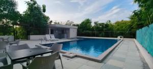 a swimming pool with a table and chairs at Namir Jungle Retreat Formerly Orchids Jungle Camp in Chandrapur