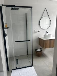 a glass shower door in a bathroom with a sink at The Spear Guest Lodge in Graskop +12 photos