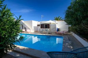 une piscine avec deux chaises et un parasol dans l'établissement Chalet Addaya, à Port d'Addaia