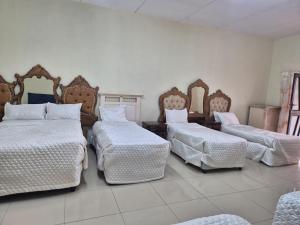 a room with four beds with white sheets and mirrors at Morogoro Park Lodge 