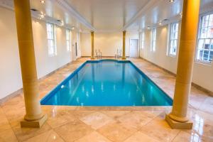 een groot zwembad in een grote kamer met zuilen bij Netley Hall in Shrewsbury