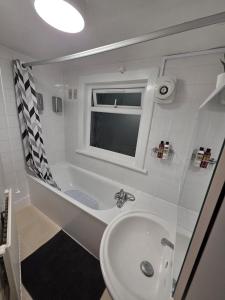 ein Badezimmer mit Waschbecken, Badewanne und Fenster in der Unterkunft Shalom Stay Tottenham in London + 25 Fotos