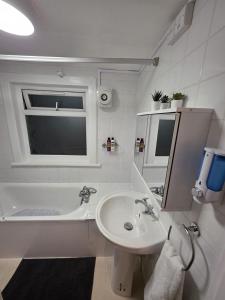 ein weißes Badezimmer mit Waschbecken und Badewanne in der Unterkunft Shalom Stay Tottenham in London