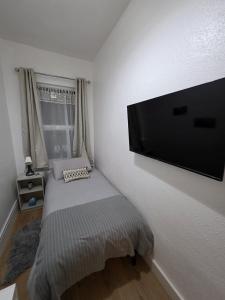 ein Schlafzimmer mit einem Bett mit einem Flachbildfernseher an der Wand in der Unterkunft Shalom Stay Tottenham in London