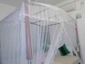 un lit à baldaquin avec des rideaux blancs dans une chambre dans l'établissement Mountain Heaven inn, à Mirissa