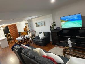 a living room with a couch and a flat screen tv at Charming Townhouse Kirra Beach in Tweed Heads
