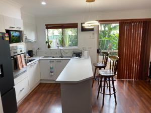 a kitchen with white cabinets and a kitchen island with bar stools at Charming Townhouse Kirra Beach in Tweed Heads