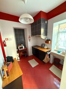a kitchen with a red tile floor and red walls at Summer Haze Ericeira in Ericeira +5 photos