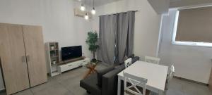 ein Wohnzimmer mit Sofa, Tisch und Fernseher in der Unterkunft Helios nest in Artemida