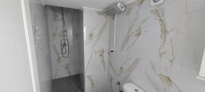 ein Badezimmer mit weißen Marmorwänden und einer Dusche in der Unterkunft Helios nest in Artemida + 15 Fotos
