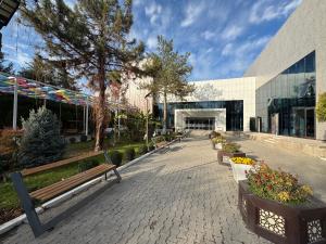 ein Park mit Bänken vor einem Gebäude in der Unterkunft Chotqol sanatorium in G‘azalkent