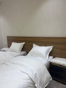 zwei Betten in einem Zimmer mit weißen Laken und Kissen in der Unterkunft Chotqol sanatorium in G‘azalkent