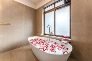 a bathroom with a white tub filled with red roses at ELIVAAS Signature Casa Del Mundo With Pvt Pool, Bar, Lift & Scenic Hill Vistas in Vagator +60 photos